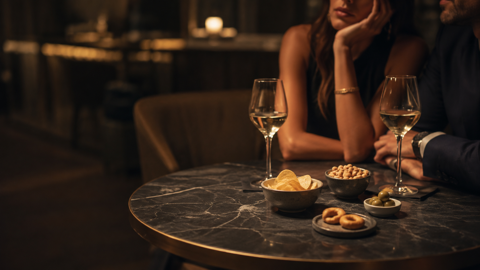 Tavolo da aperitivo con calici di vino bianco, patatine, noccioline, olive e tarallini in un wine bar intimo